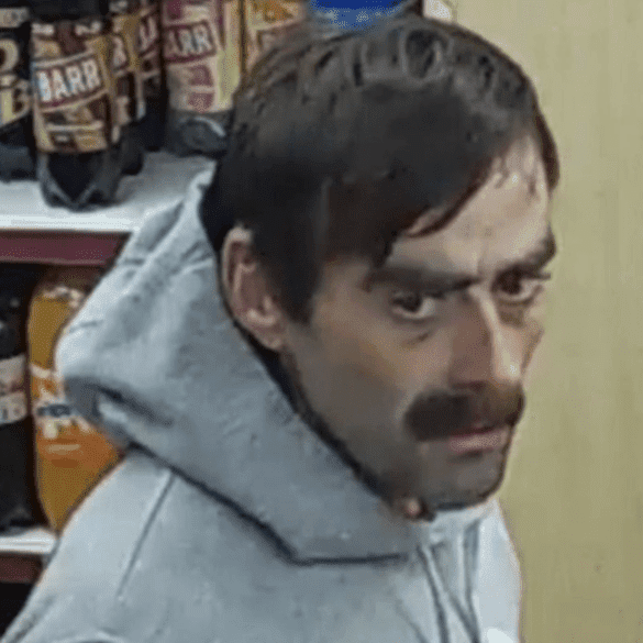 Man in hoodie with surprised expression in shop.