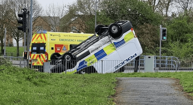A Police Vehicle Flipped Onto Its Roof Following A Collision With A Car