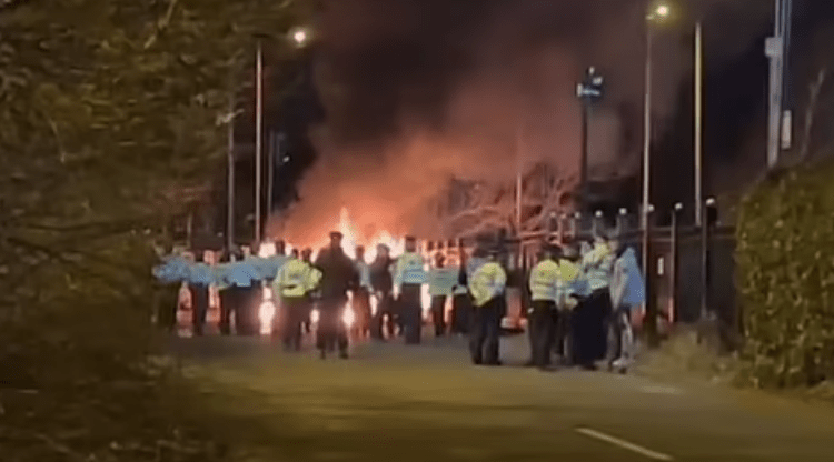 Protesters Clash With Police Outside An Asylum Seeker Hotel In Merseyside, Hurling Missiles At Officers And Setting A Police Van On Fire, As Three People Are Arrested.according To Local Mp Sir George Howarth, Social Media Sparked The Protest.the Incident Occurred In Front Of The Suites Hotel In Merseyside.