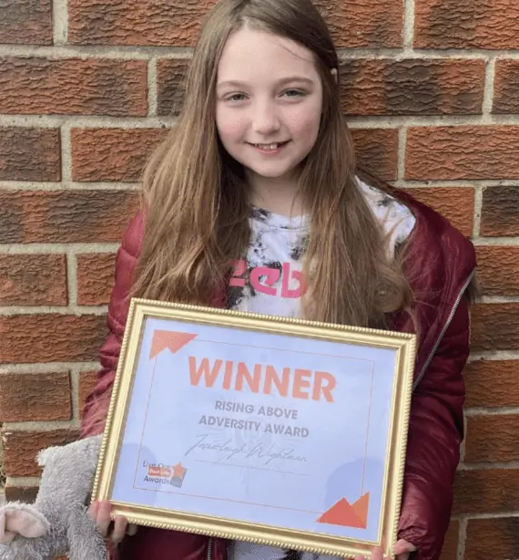 A young girl who carried on caring for others when her life was being turned upside down has been given an award for her inspirational attitude