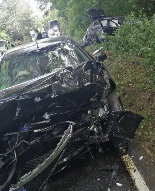The image depicts two severely damaged vehicles on the side of the road