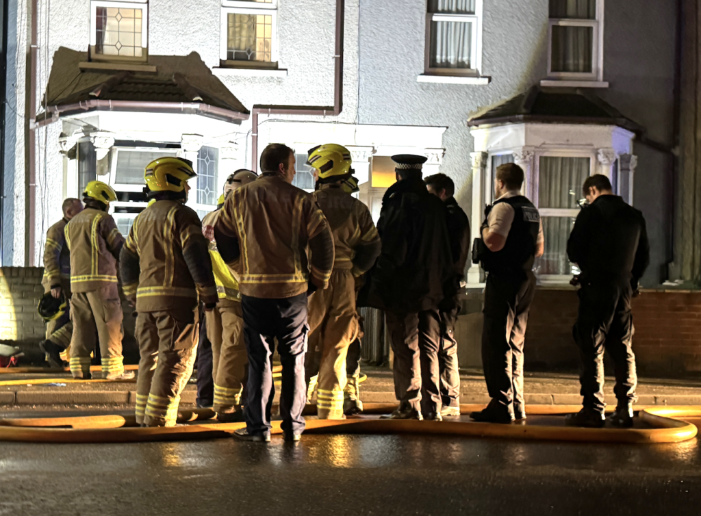 Firefighters and police at a night emergency scene.
