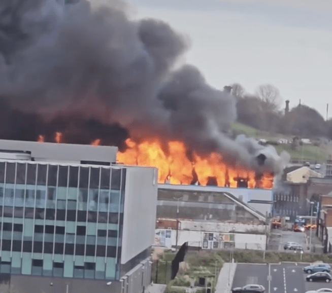 Large fire engulfs building with billowing smoke.