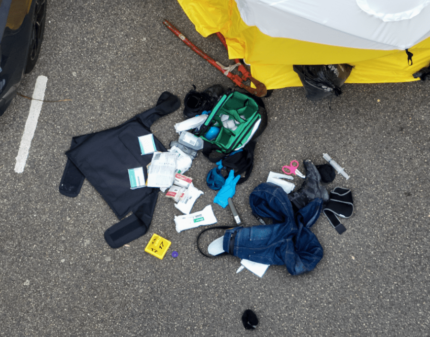 Medical supplies and clothes scattered on pavement.