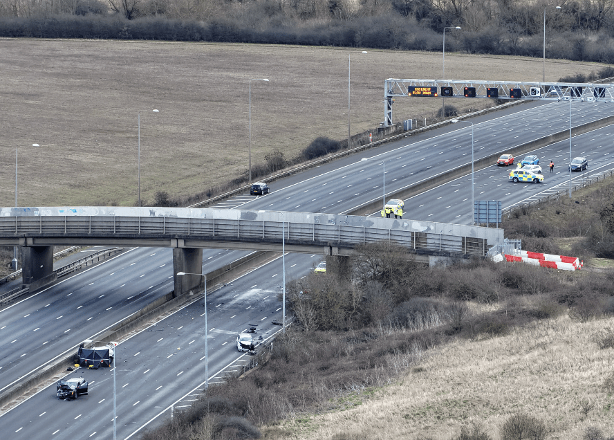 Motorway with bridge, emergency vehicles, reduced lane traffic.