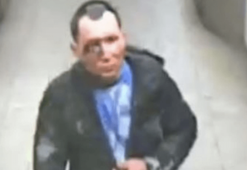 Man in jacket and blue scarf, CCTV style image.