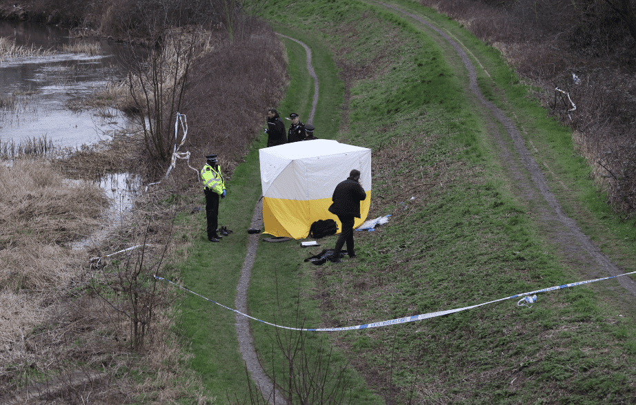 Police investigation at outdoor crime scene tent.