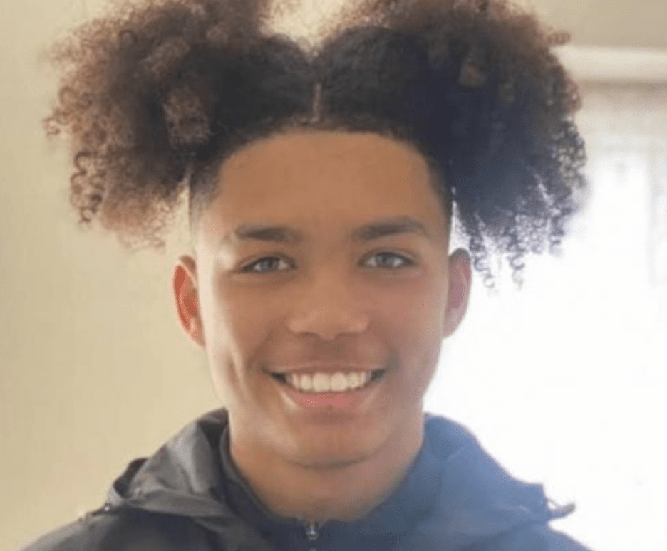 Smiling young person with unique hairstyle.
