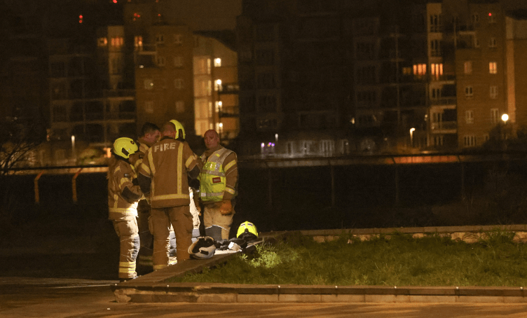 Firefighters discussing at night near residential buildings.