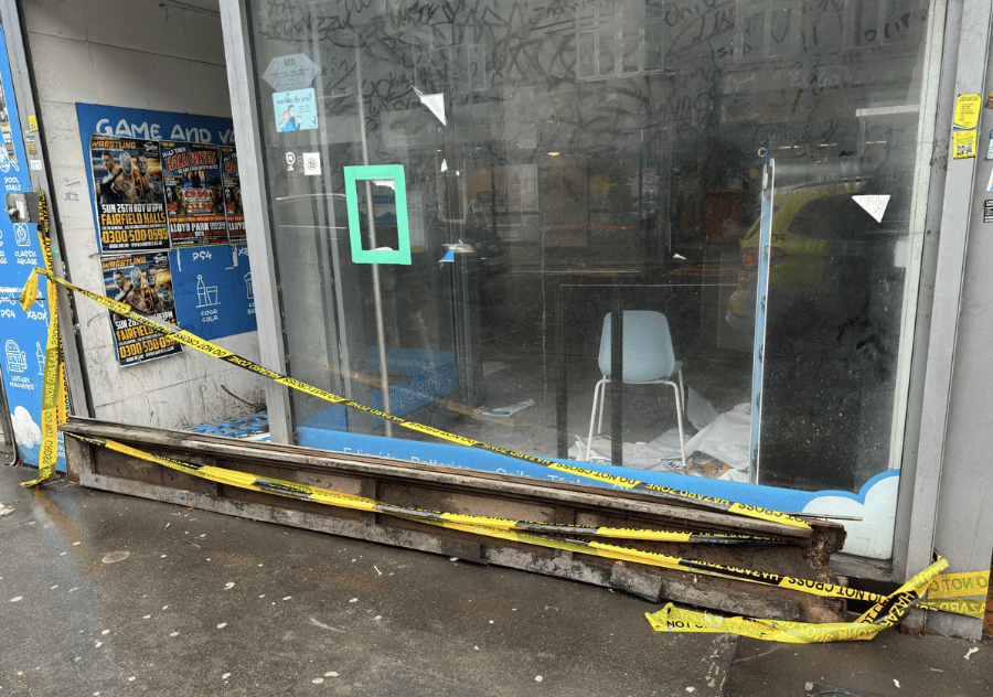 Damaged storefront with caution tape and debris.