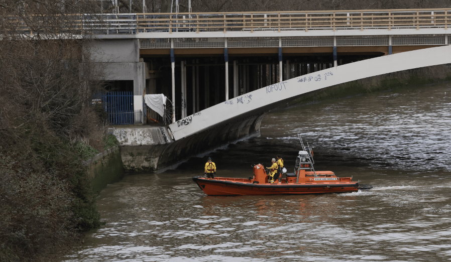 Rescue boat patrol under bridge on river.