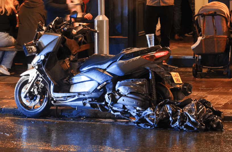 Overturned motorcycle on wet urban street at night.