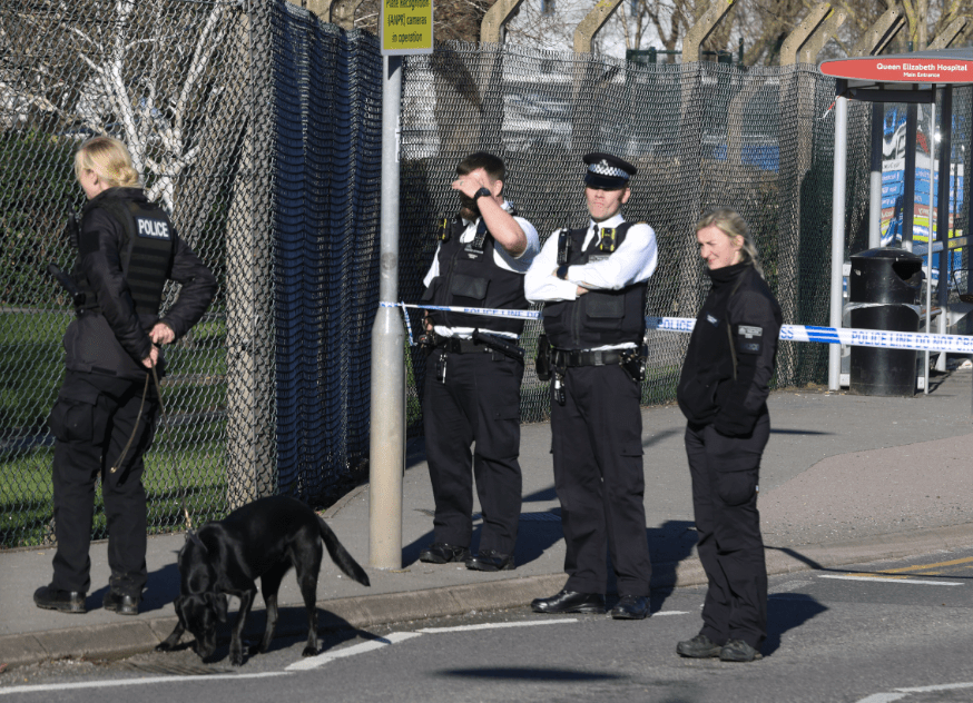UK police officers with dog at cordoned off area.