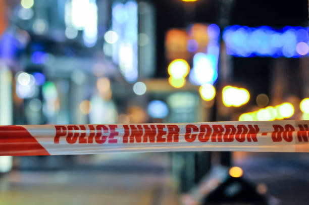 Police cordon tape seals off an area of a city at night following a crime