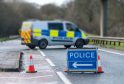 A police sign and van on a closed road.